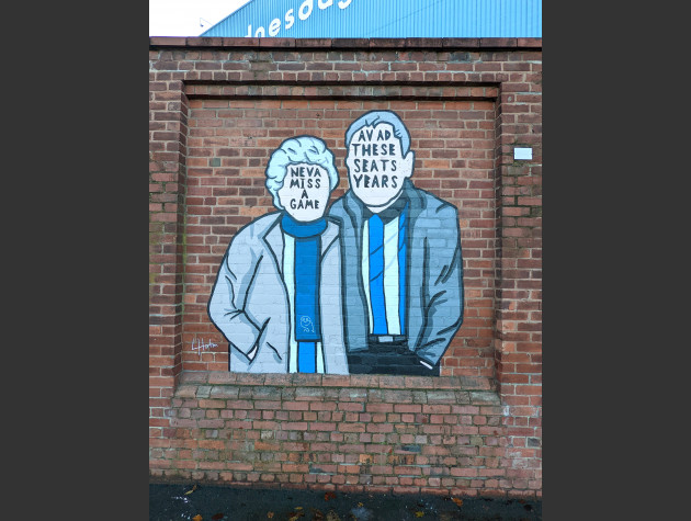 Mural of two faceless elderly Sheffield Wednesday fans with the words 'Neva miss a game' and 'these seats for years?' written over the faces