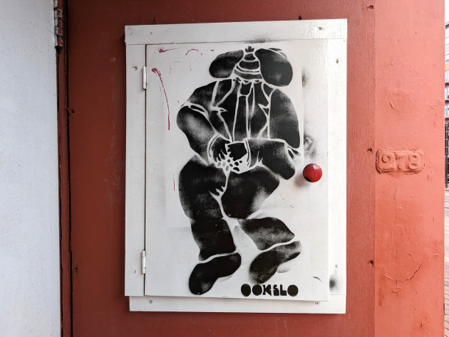Stencil artwork of a surreal character sat wearing a suit